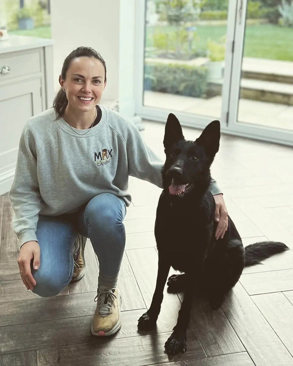 Emily with a black German shepherd in a bright garden room