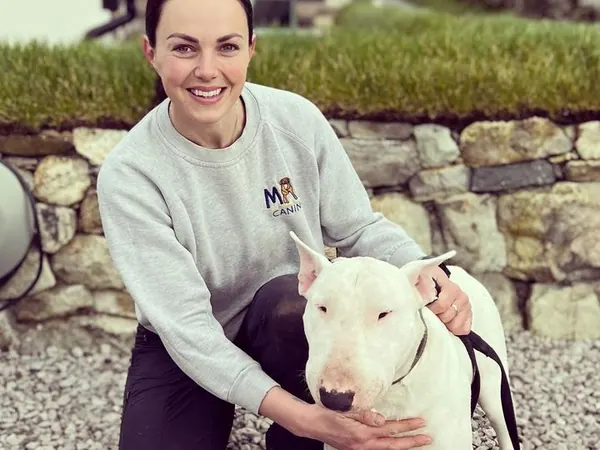 Emily kneeling beside a bull terrier
